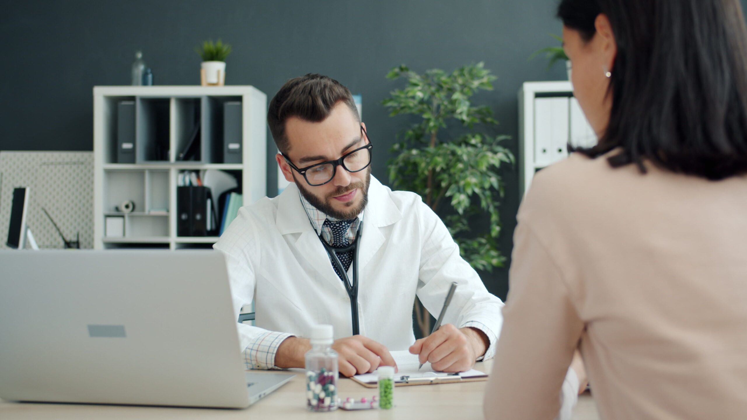 Doctor consulting a patient in a modern clinic office where an AI medical scribe could record notes