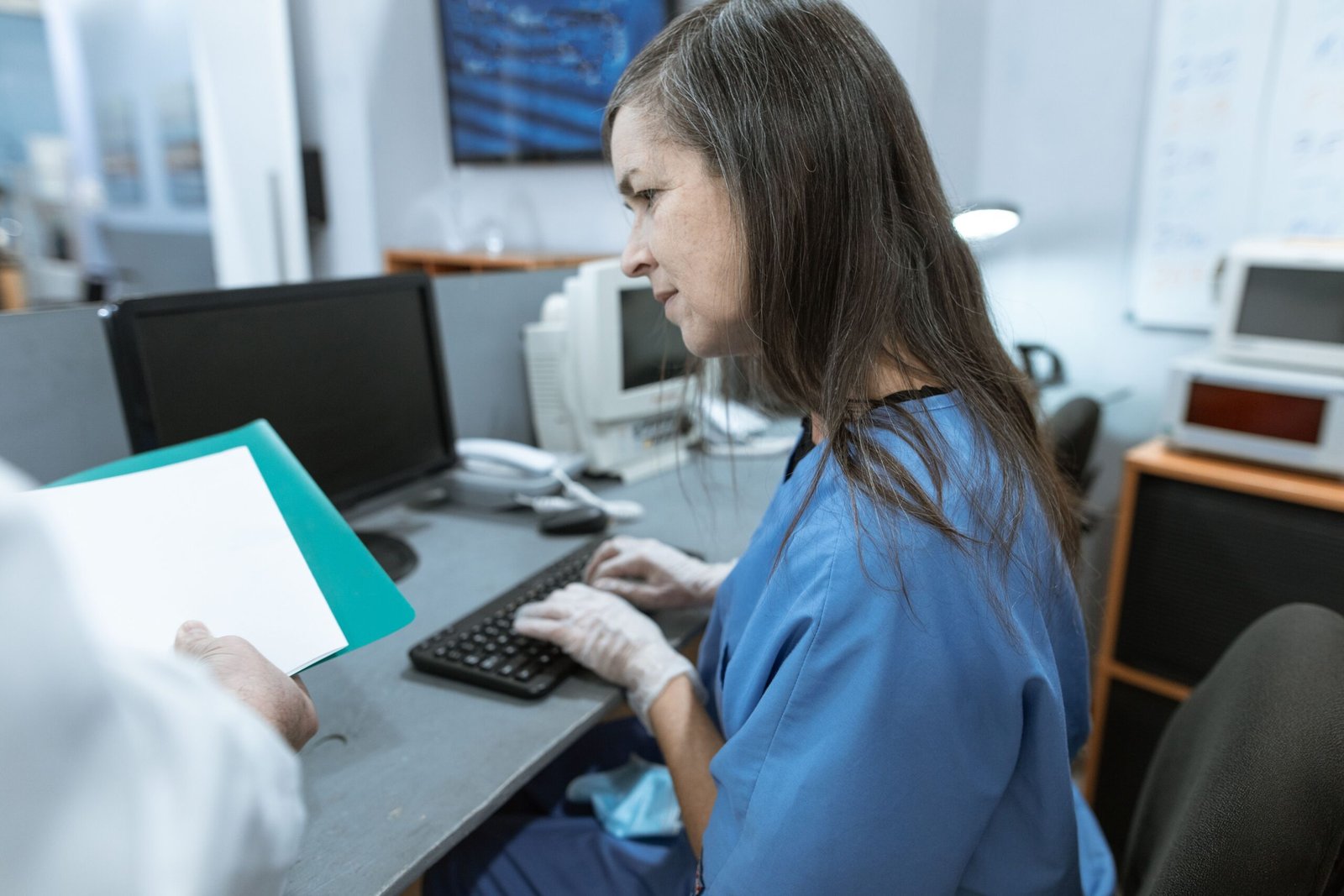 Clinic Workstation Access Control Nurse typing at a medical workstation where access control supports HIA cybersecurity requirements