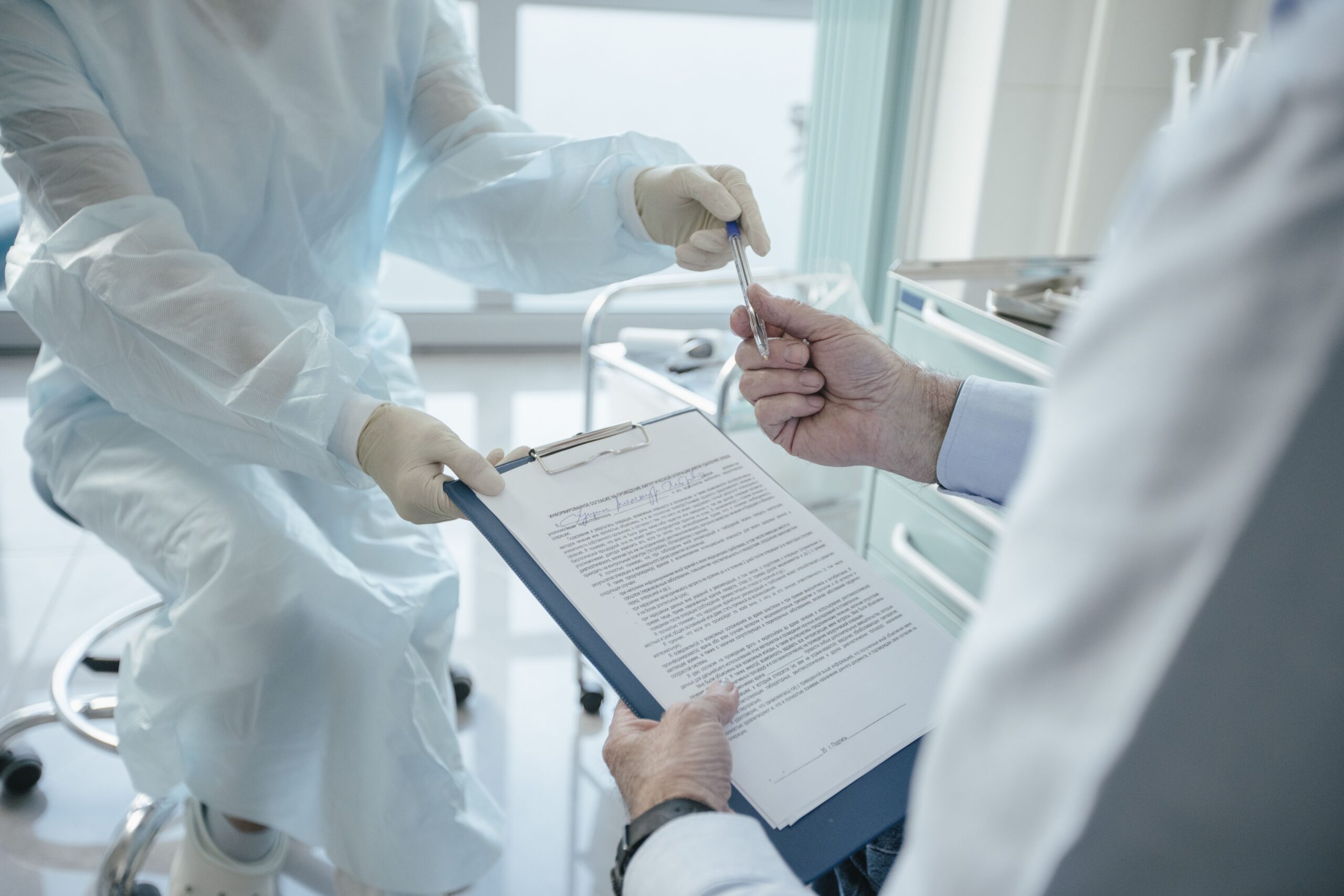 Doctor handing a clipboard to a patient to sign a consent form for disclosure to insurers